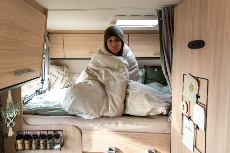 Camper fail: Alice auf dem Wohnmobilbett mit Mütze und in Decke eingewickelt