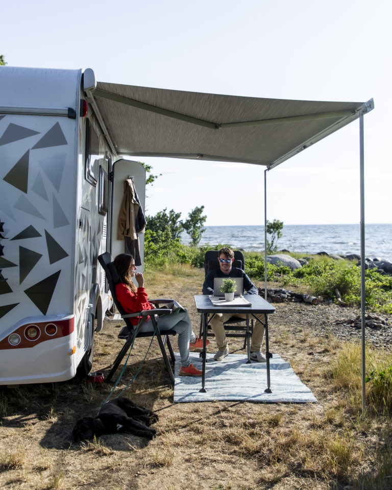 Sitzplatz unter der Markise am Meer mit Campingstühlen und -tisch als Erstausstattung fürs Wohnmobil