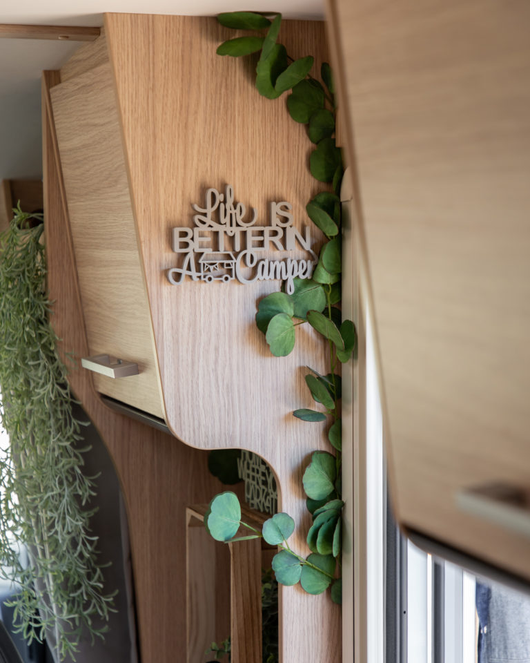 Seitenwand im Wohnmobil mit Schriftzug und Kunstpflanzen als Camping Deko Idee