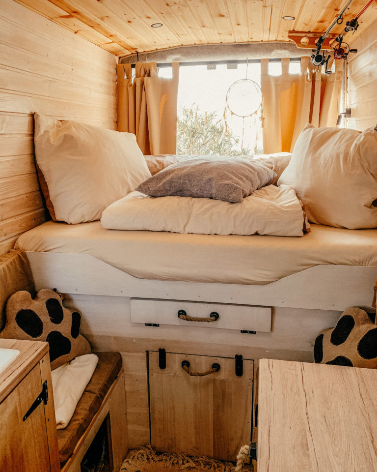 Blick auf das ausziehbare Bett im selbstausgebauten Kastenwagen mit Deko Inspiration